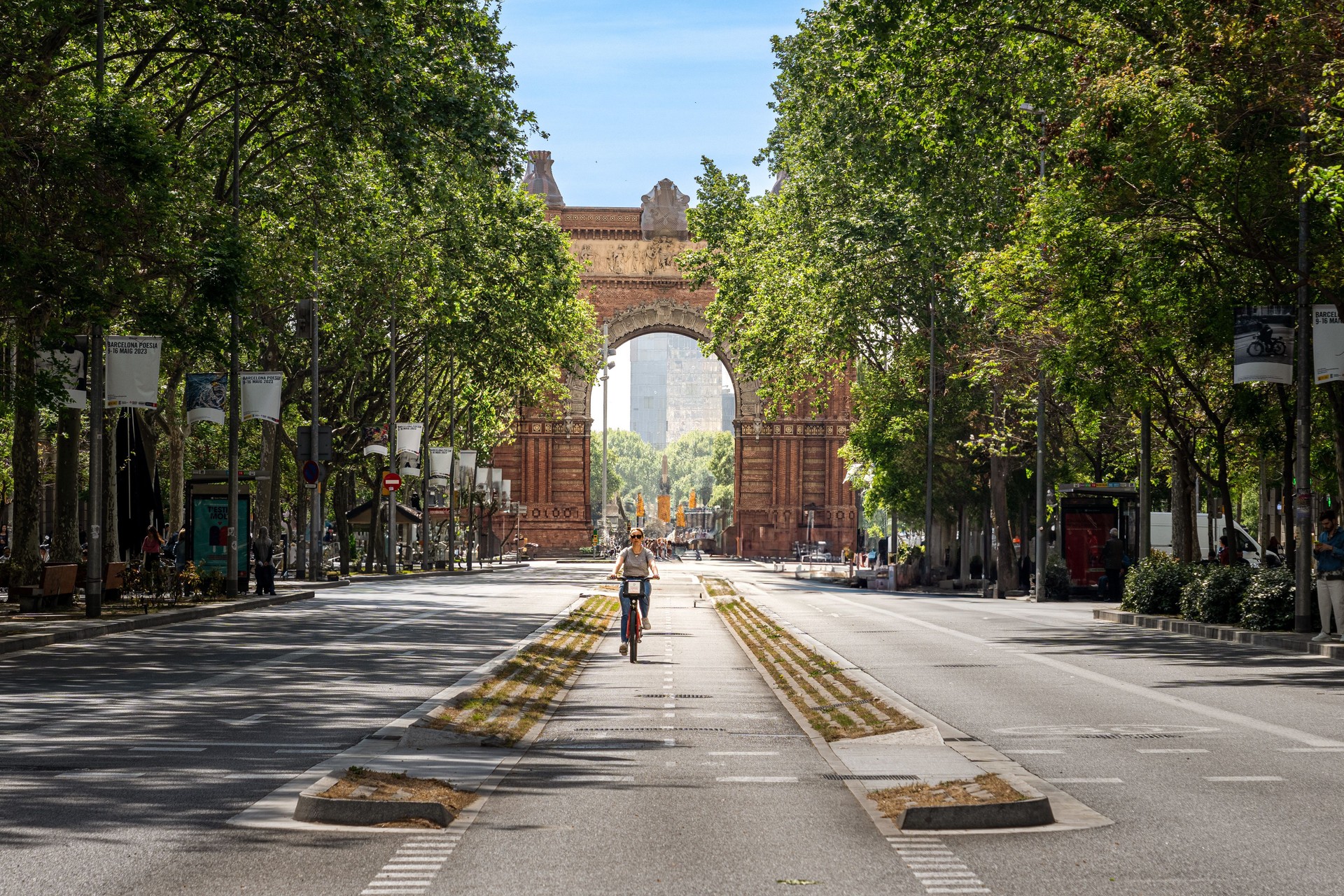 a bike rider passes in front of an arch, in barcelona